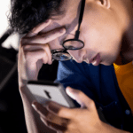 Teen boy looking at phone with head in hand