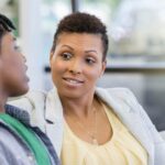 Mother talking to teen son on couch about child Apple ID