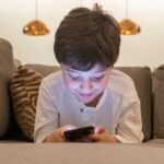 child using phone on couch