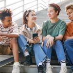 group of teens sitting together with phone