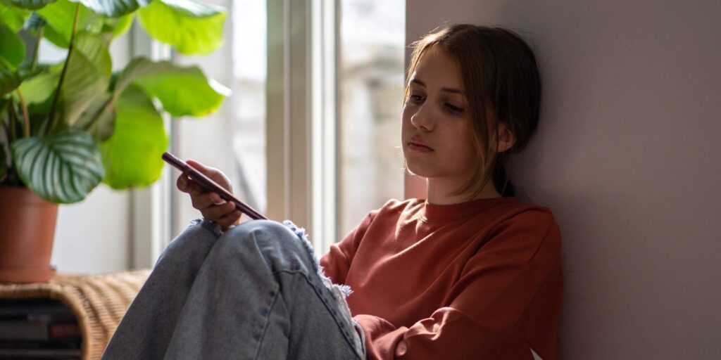 Young girl looking morose while leaning against wall